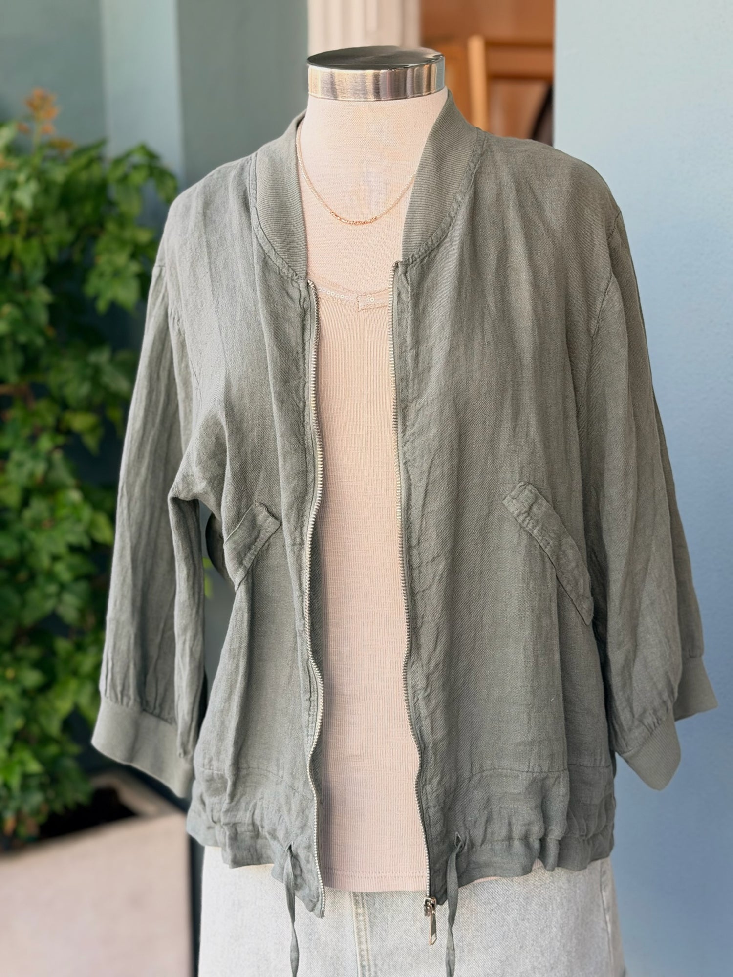 Lia Linen Jacket in olive made in Italy featuring a lightweight linen fabric zip front pockets and adjustable drawstring hem styled on mannequin