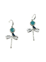 Woman wearing Lila Dragonfly Earrings in Silver, featuring textured silver dragonfly charms, turquoise-blue stones, and deep blue accents with fishhook closures.