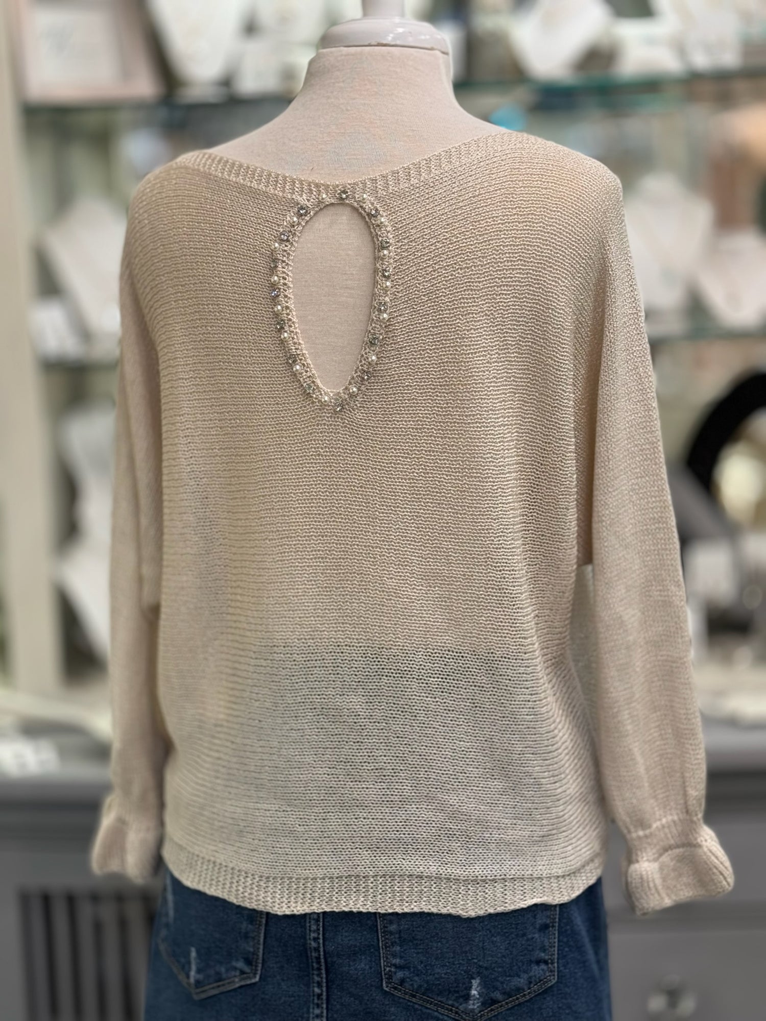 Back of knit sweater featuring an oval keyhole opening framed with pearls and rhinestones.