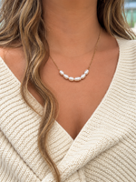 Luna Faux Keshi Pearl Necklace featuring seven irregular white faux pearls on a delicate gold-tone chain, styled with a cream knit wrap.