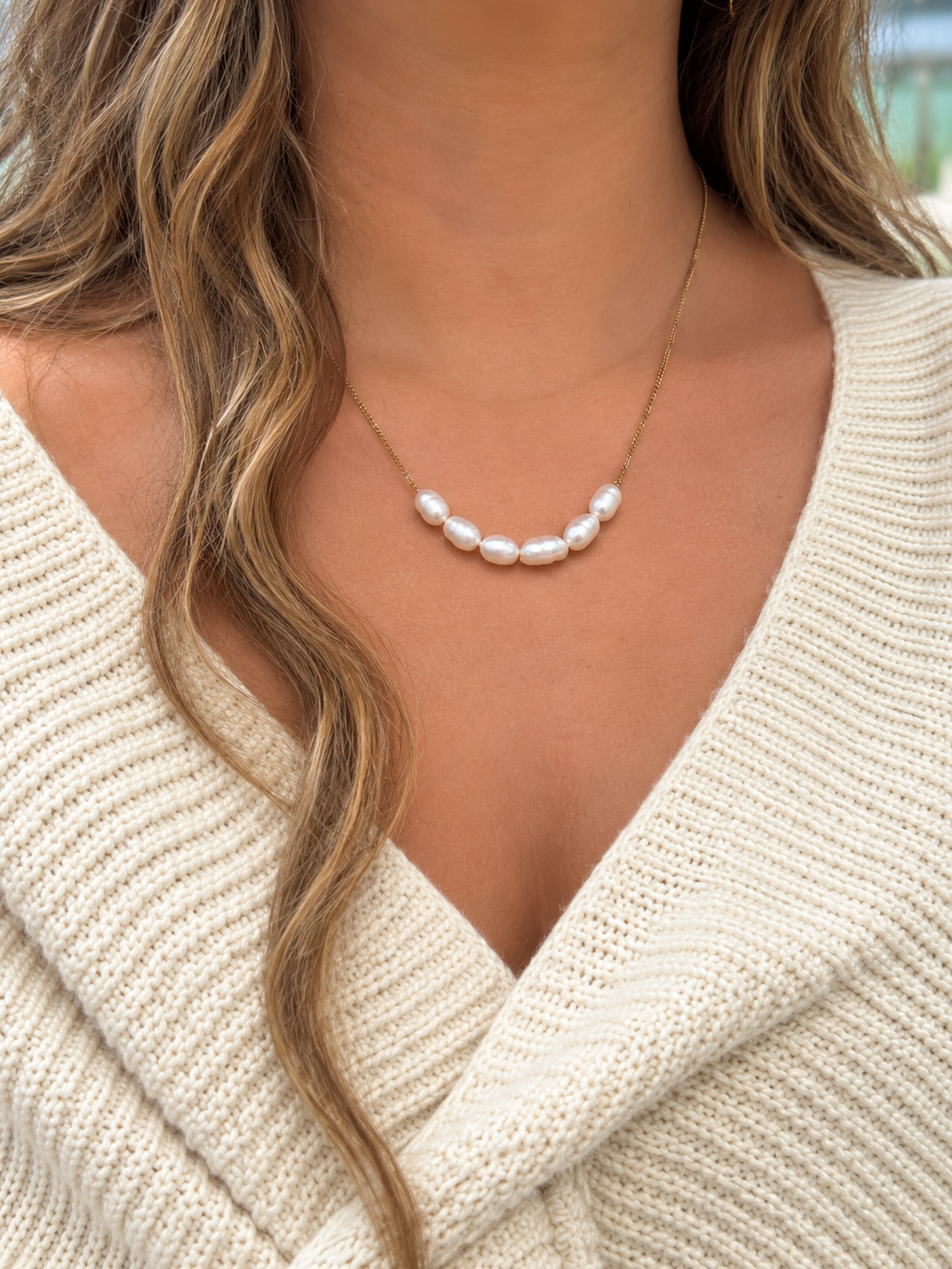 Luna Faux Keshi Pearl Necklace featuring seven irregular white faux pearls on a delicate gold-tone chain, styled with a cream knit wrap.