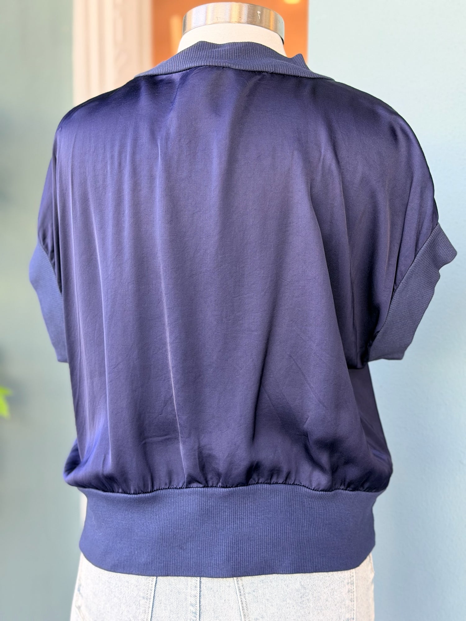 Navy blue satin top on a mannequin against a light background