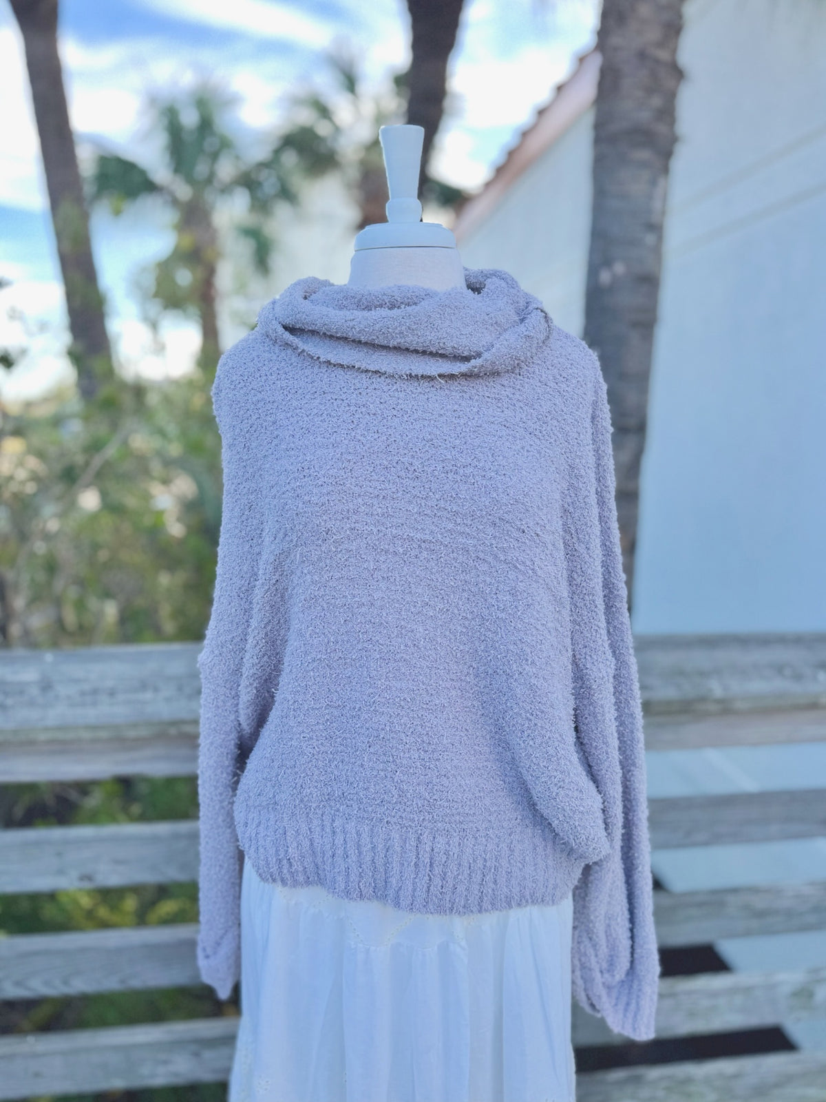 Soft grey fuzzy knit sweater with a cowl neck on a mannequin outdoors with a white skirt