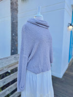 Soft grey fuzzy knit sweater with a cowl neck on a mannequin outdoors with a white skirt side view 