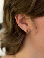 A pair of small gold crescent moon stud earrings being worn