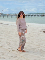 Model wearing Briella taupe shimmer sweater styled with printed pants on the beach