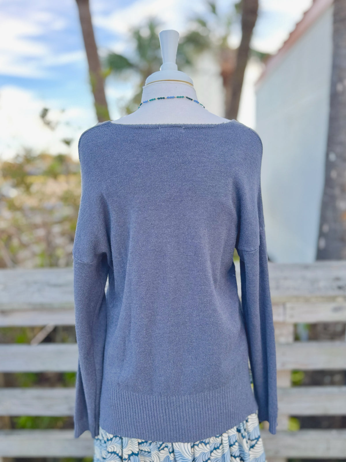Dark grey knit sweater with blue beaded necklace back view