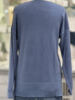 Back view of dusty blue knit sweater with relaxed fit, long sleeves, and thick ribbed hem detail.