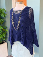 Navy blue crochet top on a mannequin with a necklace, against a light blue wall.