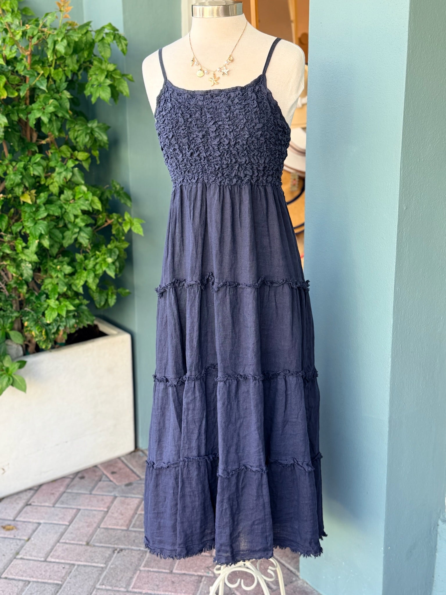 Navy tiered sleeveless dress with textured bodice and spaghetti straps displayed on mannequin
