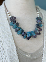 Close-up of a blue statement necklace styled with the Isabelle Sweater Cardigan at Ardor Boutique.