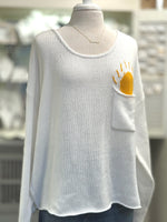 Cream open-knit scoop neck sweater with Sun design poking out of front chest pocket from Ardor Boutique