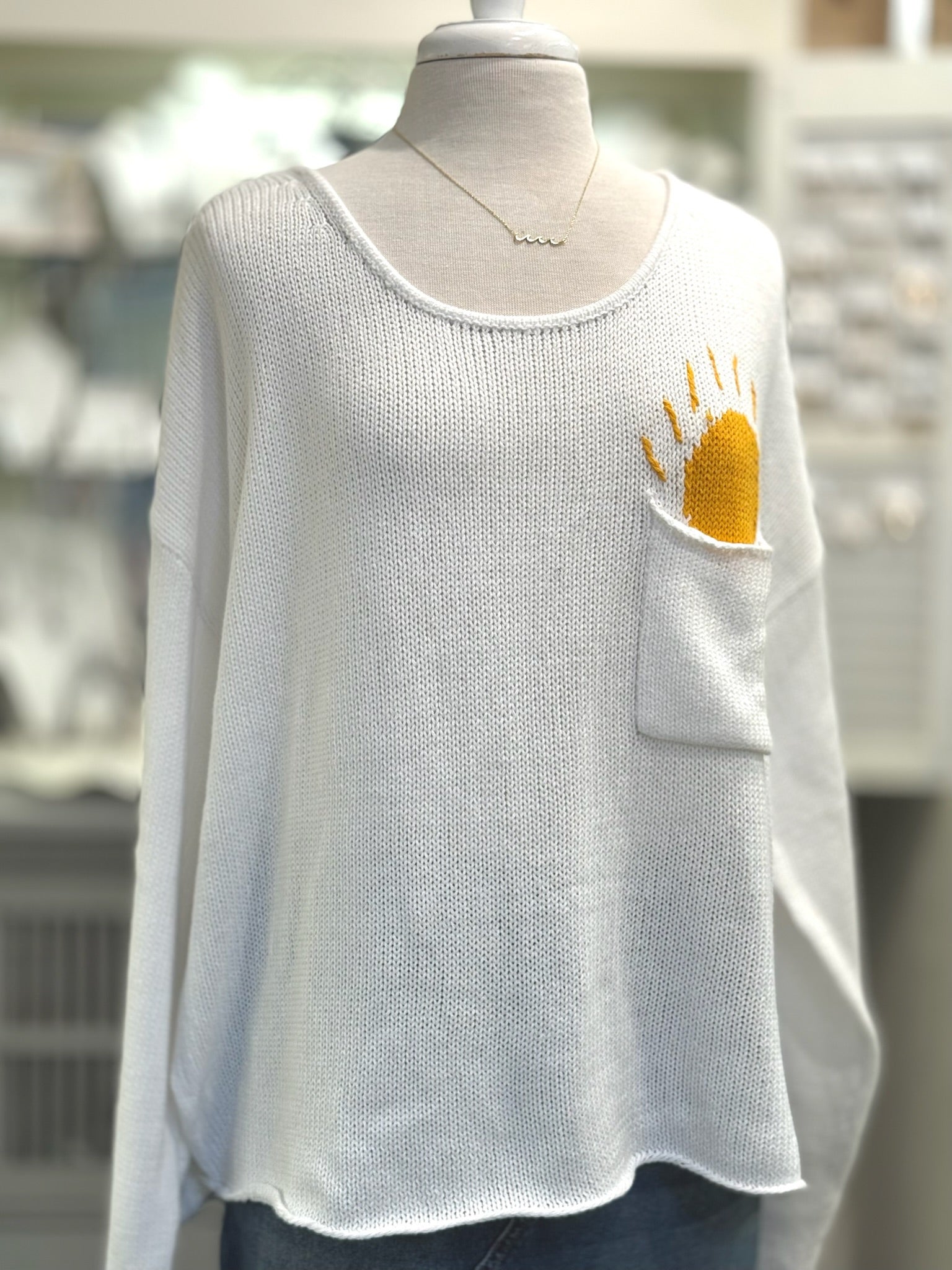 Cream open-knit scoop neck sweater with Sun design poking out of front chest pocket from Ardor Boutique