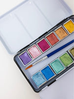 Watercolor paint set with a brush on a light background