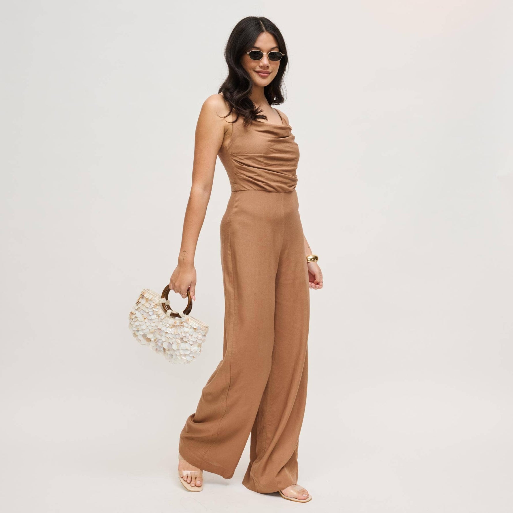 Model carrying the Scarlett Evening Bag by its polished wood ring handles, highlighting the layered shell disc exterior and sculptural silhouette.