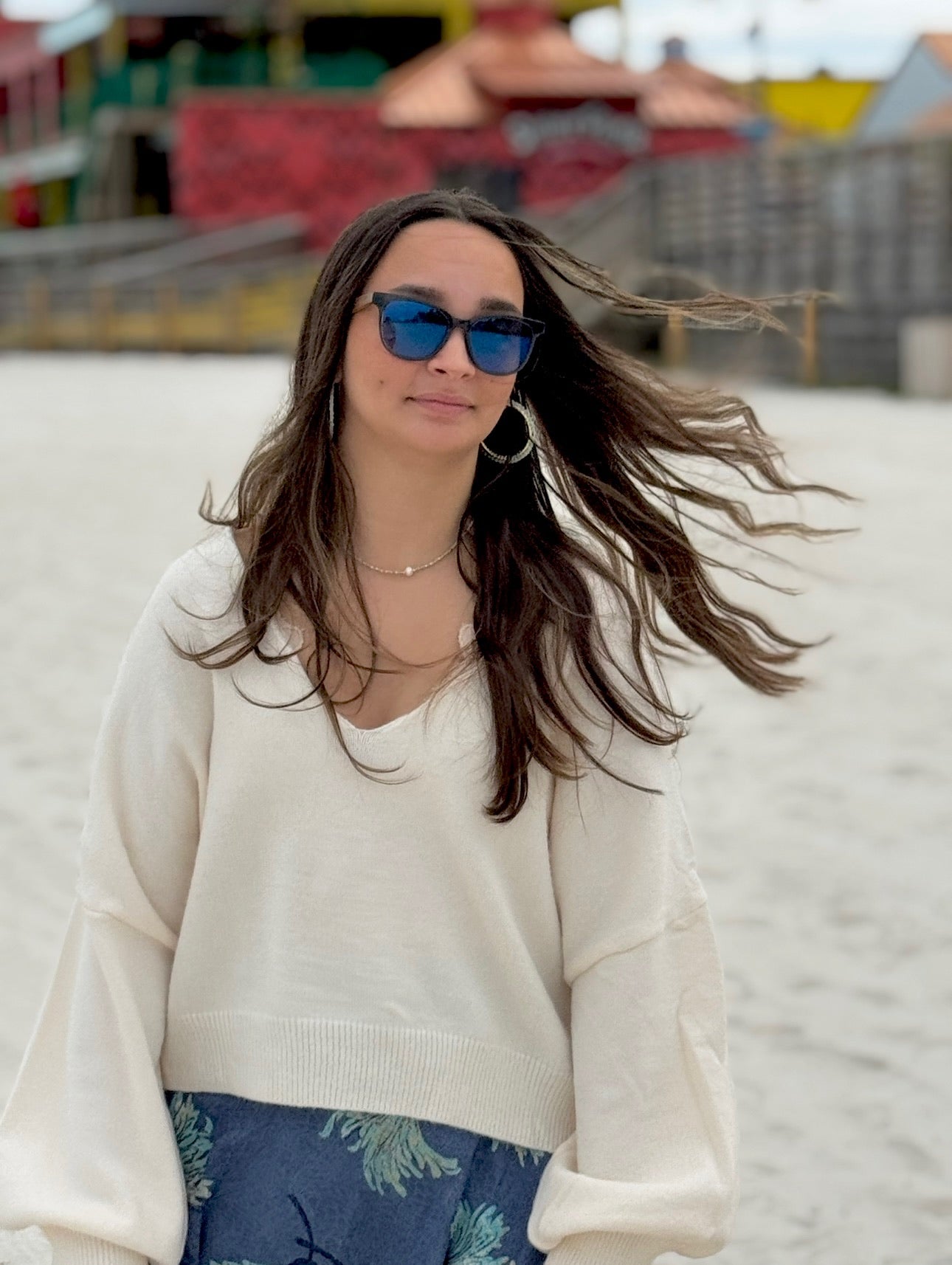 Ren Reversible Cream Sweater on model styled with aqua jewelry, blue sunglasses, and aqua blue skirt