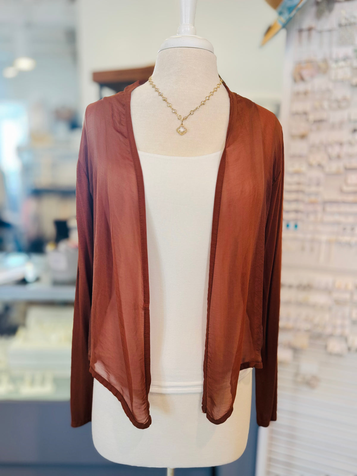 Rust lightweight cardigan worn open over a white tank.