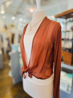 Rust lightweight cardigan with long sleeves and a front tie, styled over a white tank with a gold necklace.