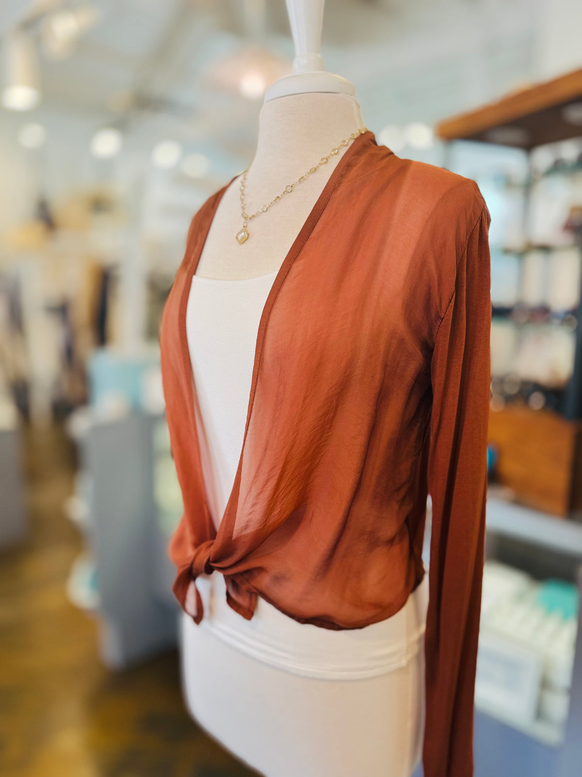 Rust lightweight cardigan with long sleeves and a front tie, styled over a white tank with a gold necklace.