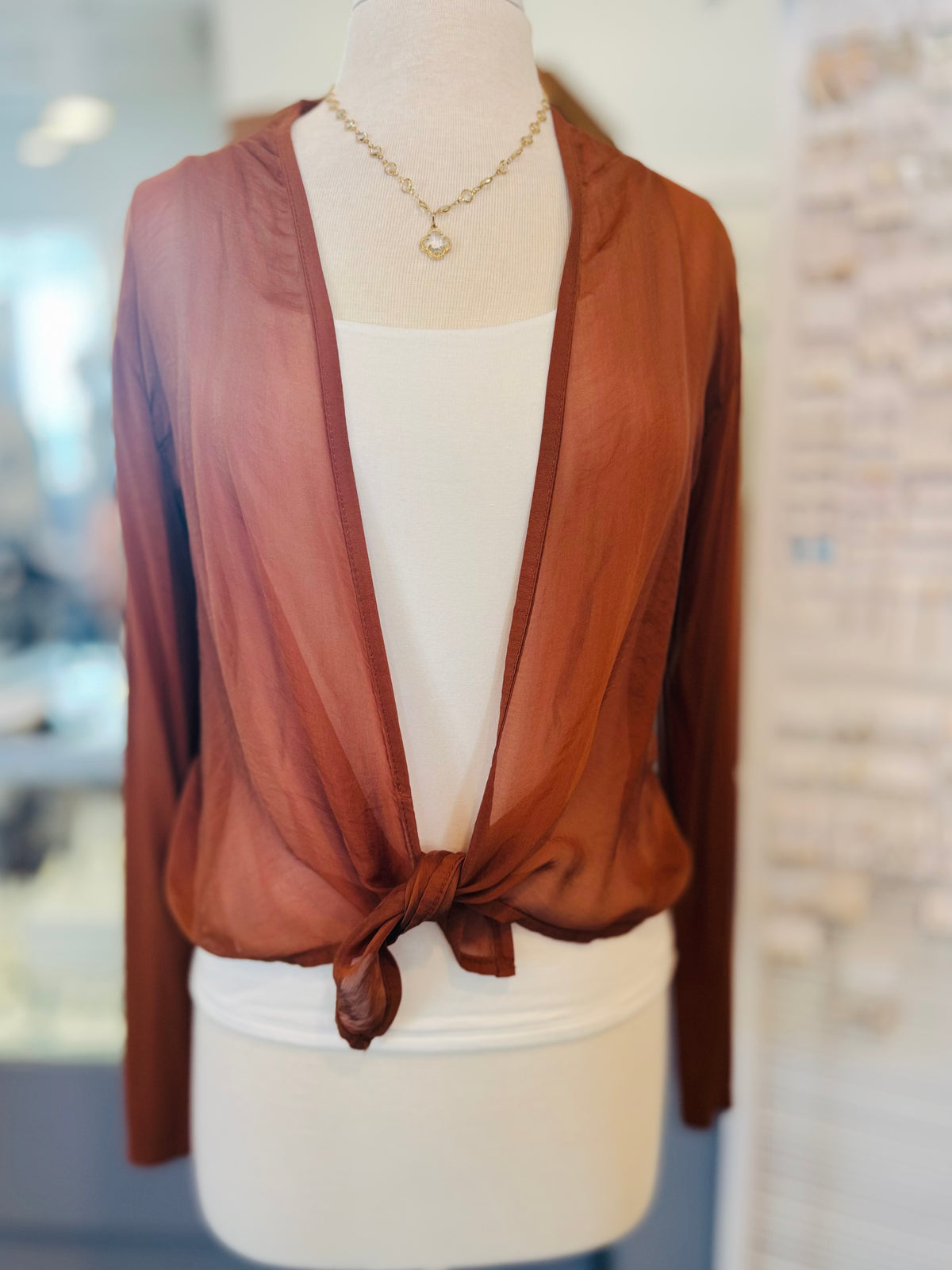 Front view of a rust-colored lightweight cardigan tied at the waist, featuring long sleeves and flowing fabric.