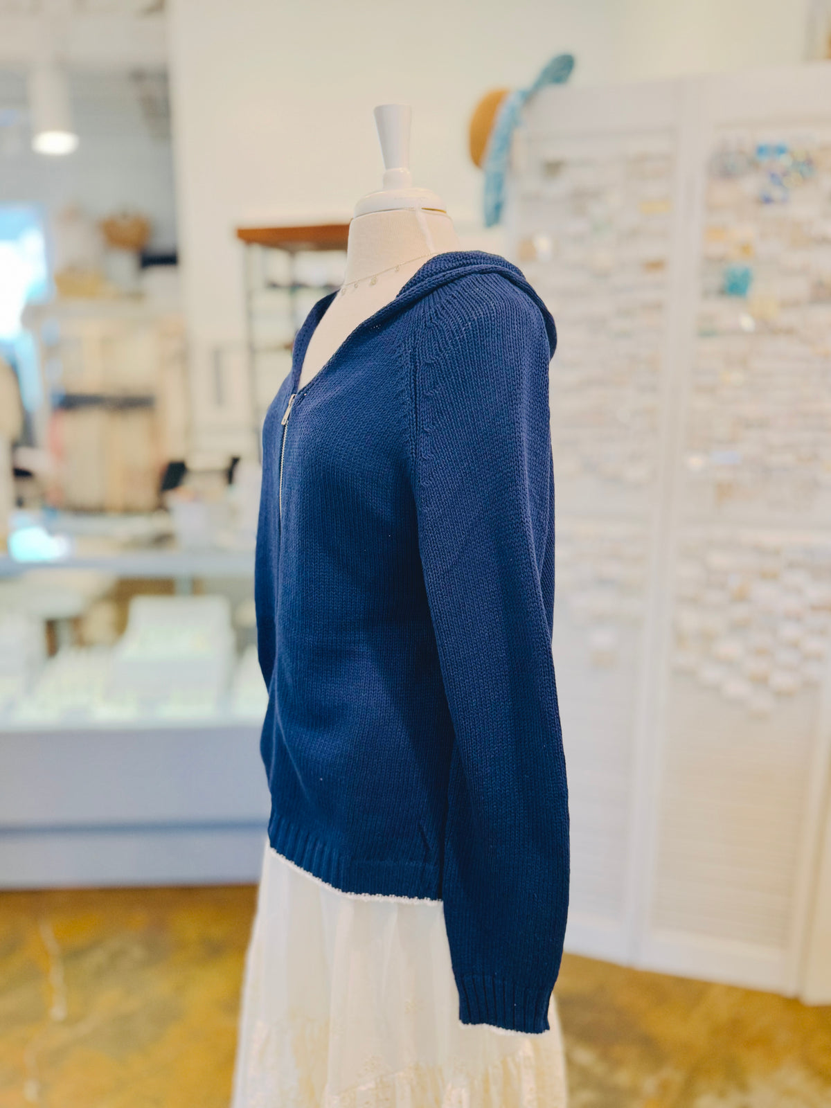 Side view of the Sarah Sweater in Navy Blue featuring a relaxed hood, textured cotton-blend knit, long sleeves, ribbed cuffs, and gently curved hemline.