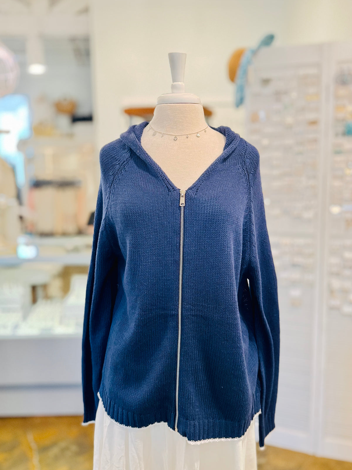 Front view of the Sarah Sweater in Navy Blue featuring a full silver zipper, relaxed hood, textured cotton-blend knit, long sleeves, and white hem trim.