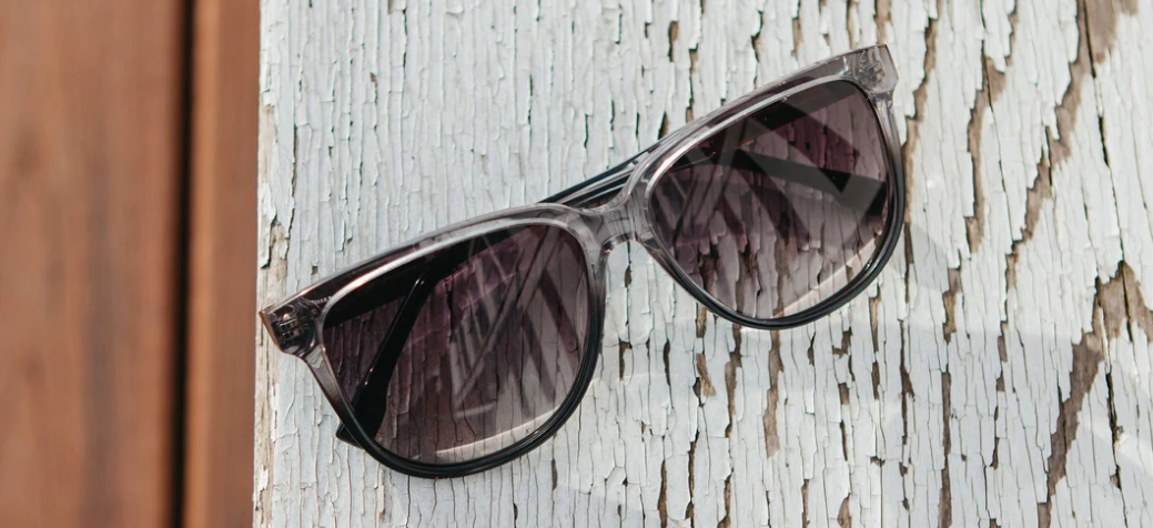 McKensie Moonlight Elm Burl Grey Fade Polarized Sunglasses styled in front on wood paneling