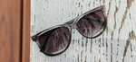 McKensie Moonlight Elm Burl Grey Fade Polarized Sunglasses styled in front on wood paneling