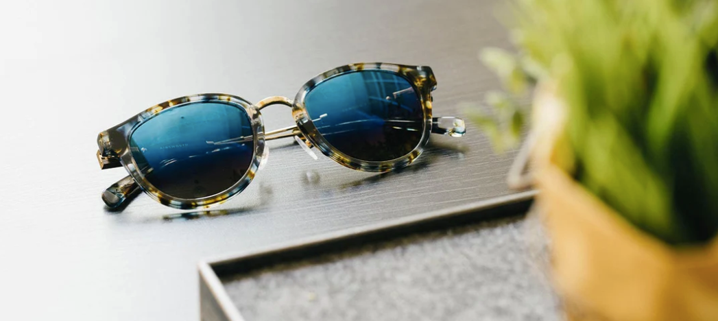 Shwood Ainsworth Blue Nebula Gold Flash Polarized sunglasses styled on wood background