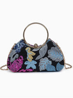 A small structured handbag with a black sequined background and colorful embroidered tropical floral motifs in blue, pink, and gold. It features a large circular metal handle and a gold chain strap, photographed on a clean white background.