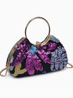 A small black sequined clutch handbag with a gold-tone circular top handle and chain strap. The bag features a vibrant floral pattern with purple, pink, blue, and gold sequins on a white background.