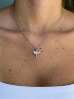 Silver necklace with a dragonfly pendant on a person's neck against a light background