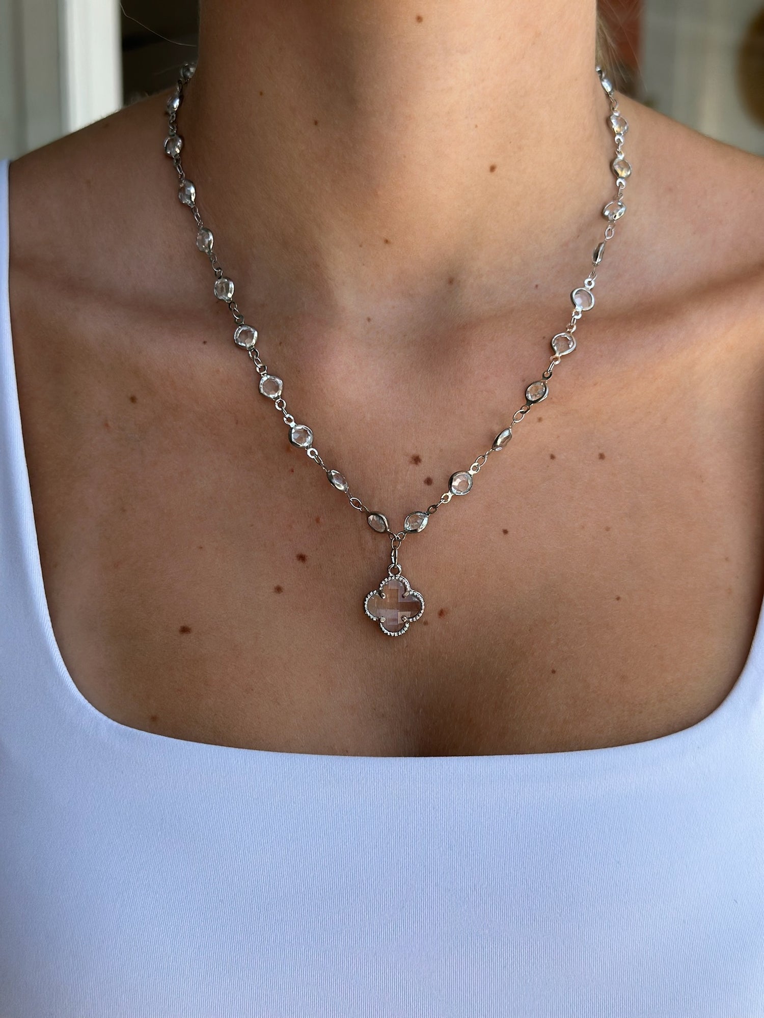 Silver necklace with a pendant on a person wearing a light blue top.