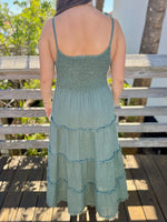 woman wearing a green dress with a wooden deck and trees in the background