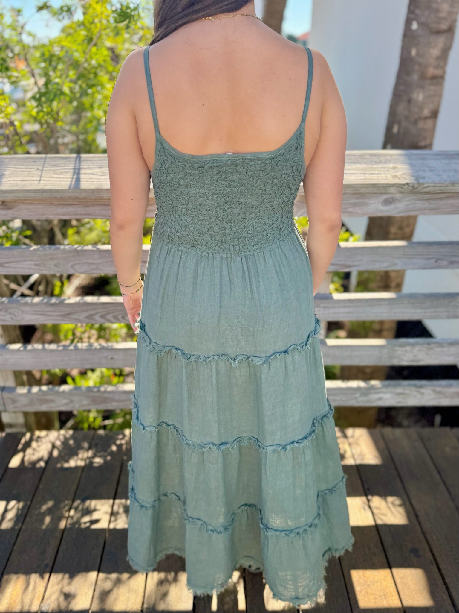 woman wearing a green dress with a wooden deck and trees in the background