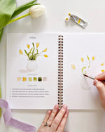 Open Spring watercolor workbook by Emily Lex showing tulips painting lesson with color palette instructions and outlined sketch to paint