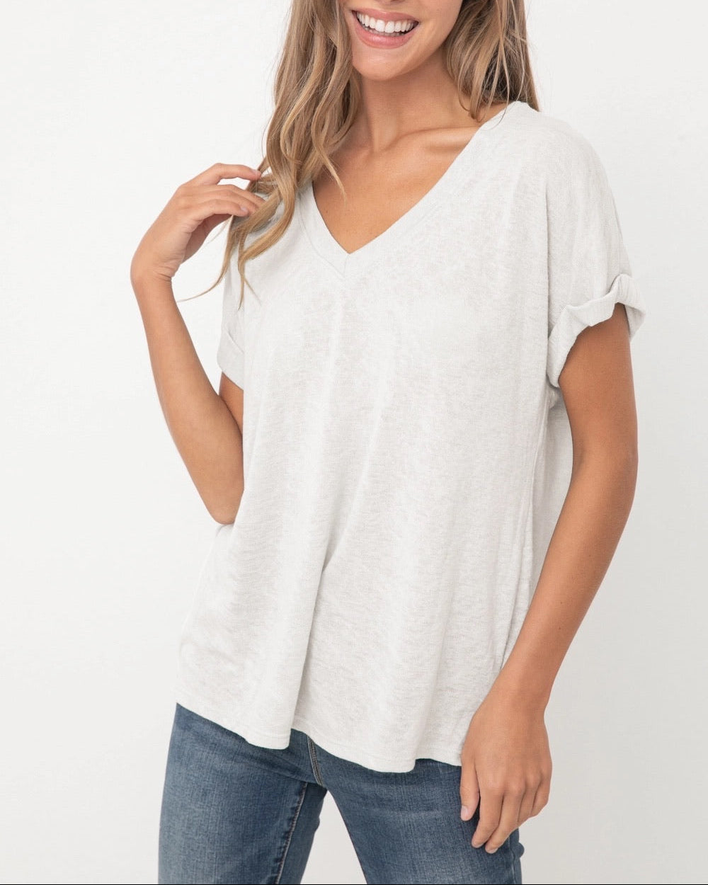 Model wearing the white Terri V Neck Tee with a relaxed silhouette, soft lightweight fabric, V neckline, and cuffed short sleeves from Ardor Boutique.