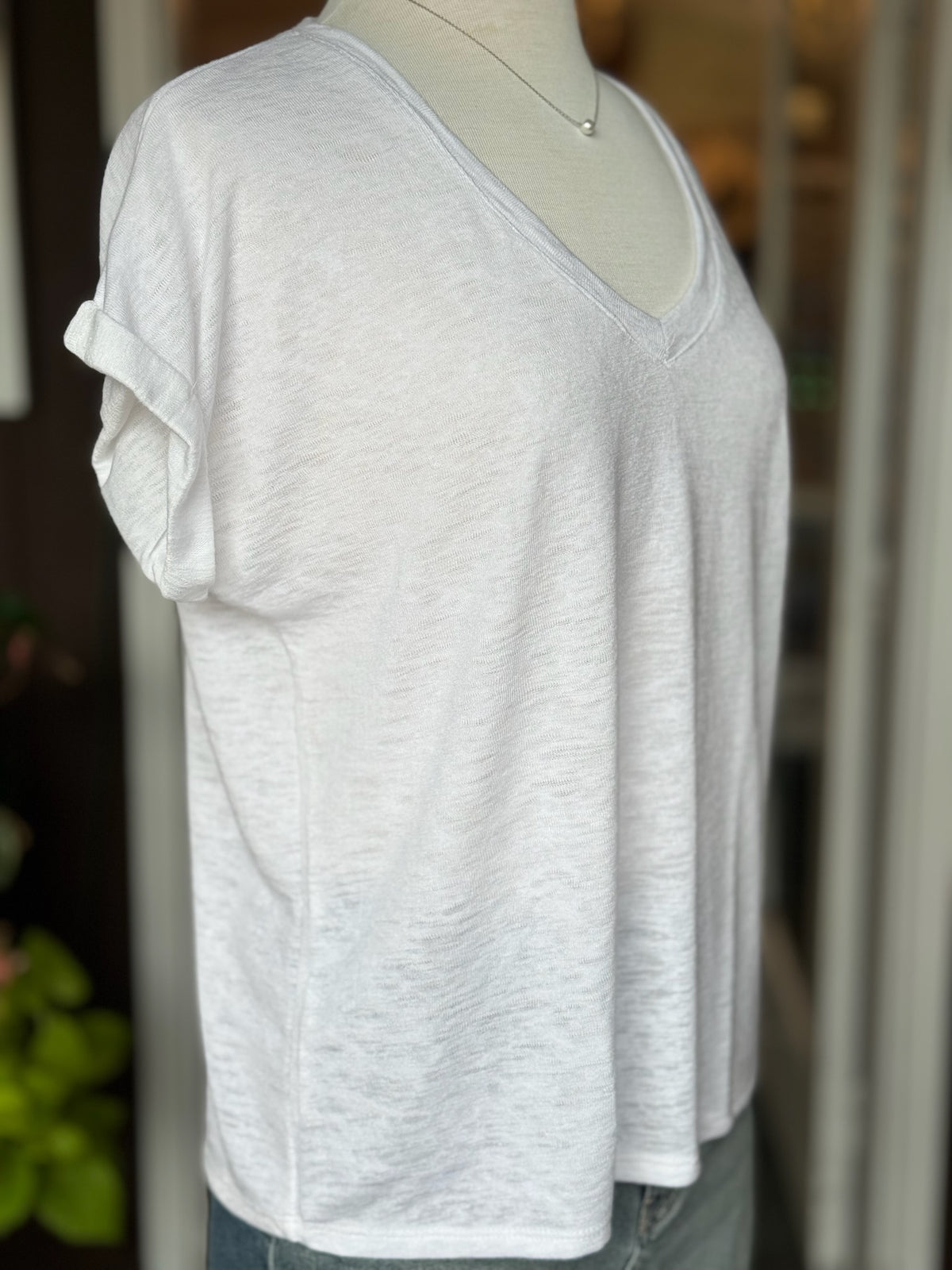 Side view of the Terri V Neck Tee in white highlighting the relaxed drape, V neckline, and cuffed short sleeve detail at Ardor Boutique.