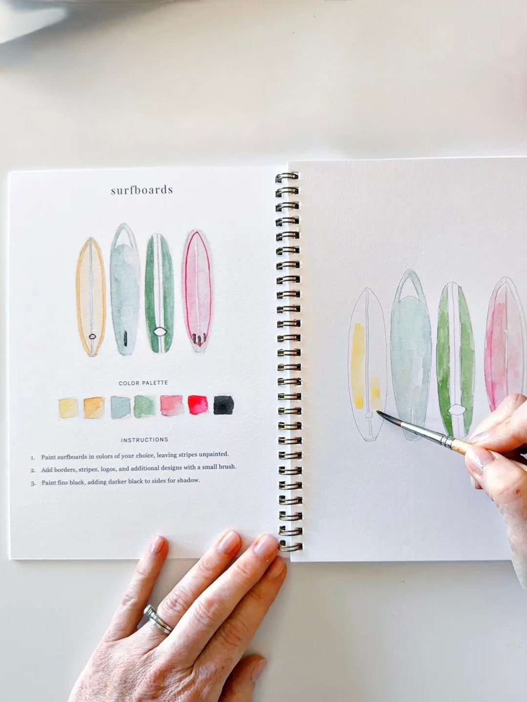 Example from book: Open book with illustrations of surfboards with step by step instructions
