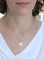 Woman wearing layered Nina Halls necklaces, including the Veronica White Keshi Freshwater Pearl Necklace with sterling silver and rose gold chain, paired with a delicate rose gold necklace featuring tiny white pearls. Styled with a white draped neckline top.