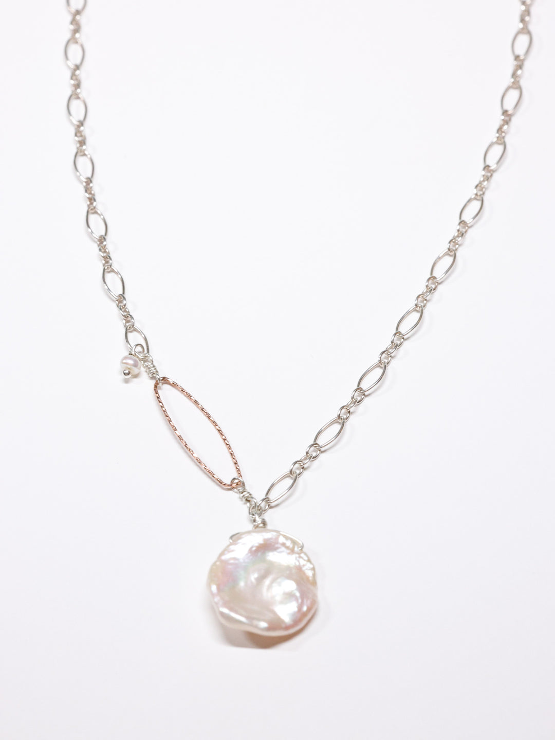 Handcrafted necklace featuring a large white Keshi freshwater pearl pendant on a sterling silver chain with a hammered rose gold oval accent and small pearl detail. Limited edition Nina Halls design, exclusive to Ardor Boutique.