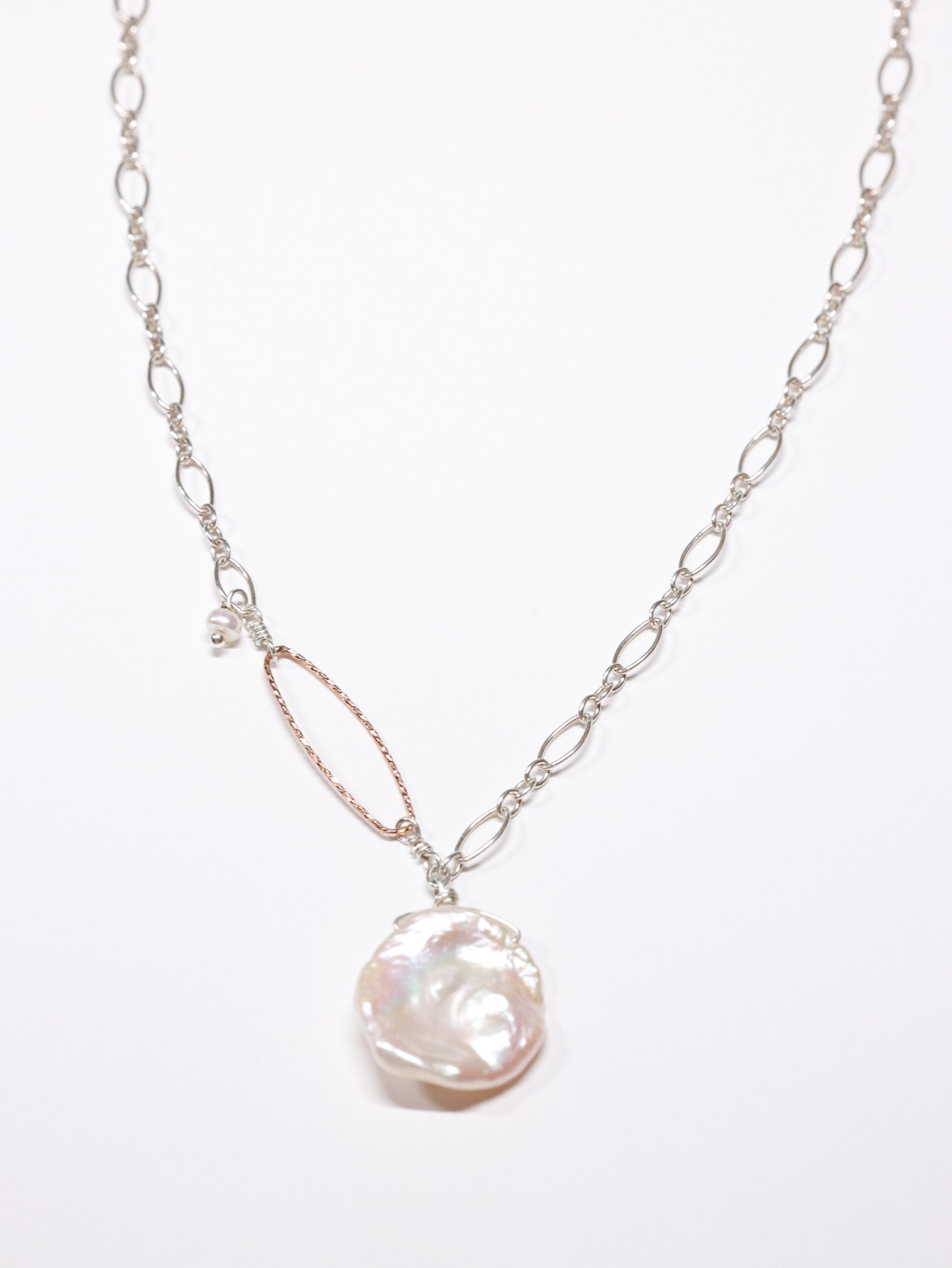 Handcrafted necklace featuring a large white Keshi freshwater pearl pendant on a sterling silver chain with a hammered rose gold oval accent and small pearl detail. Limited edition Nina Halls design, exclusive to Ardor Boutique.
