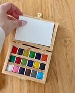 Open watercolor paint set in an eco friendly bamboo box with 18 vibrant watercolor pans and removable mixing tray paintbrush not included