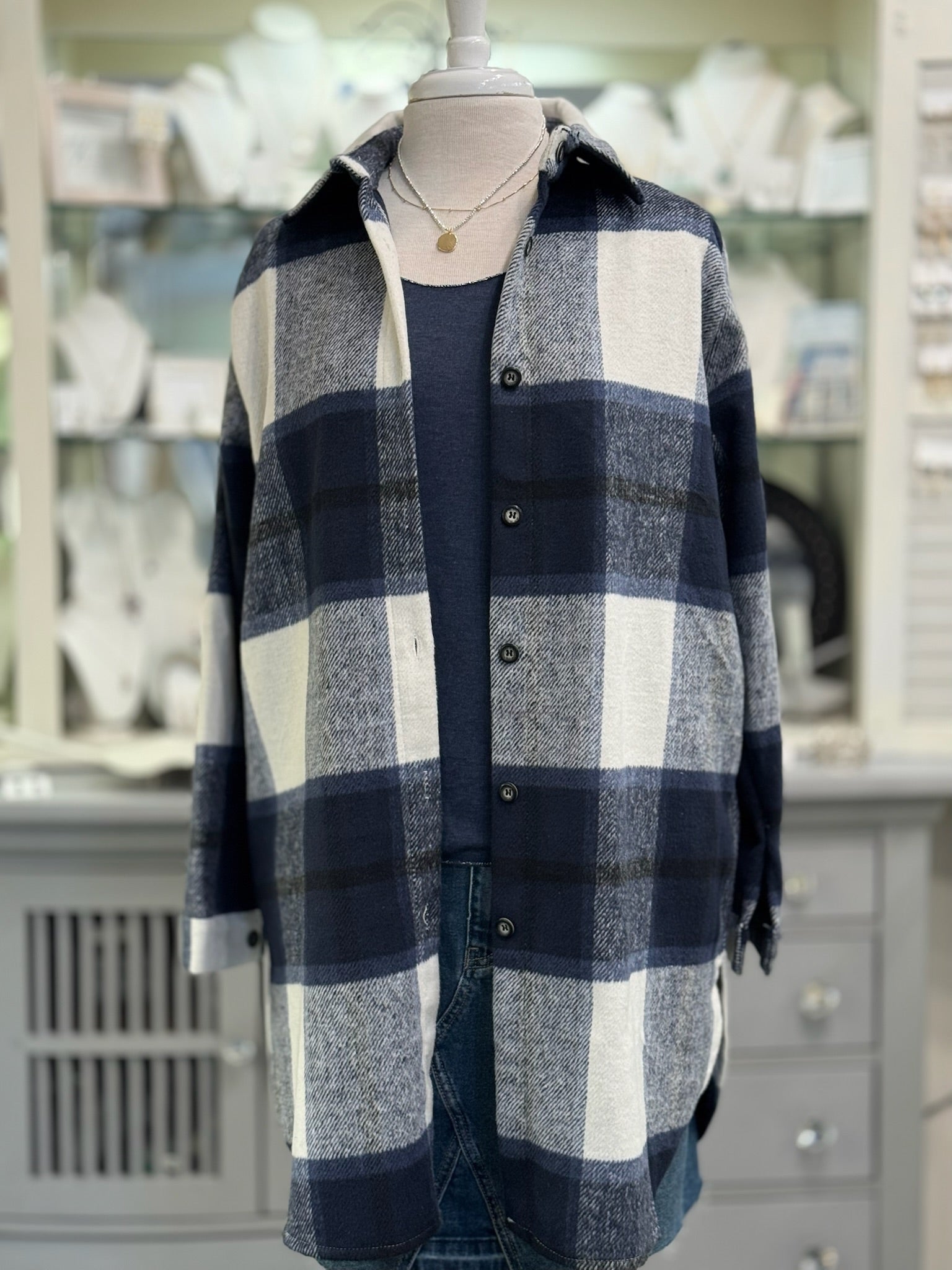 Women’s outfit featuring navy plaid shacket layered over navy tee and denim for casual chic style.