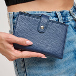 Person holding a blue wallet with jeans in the background