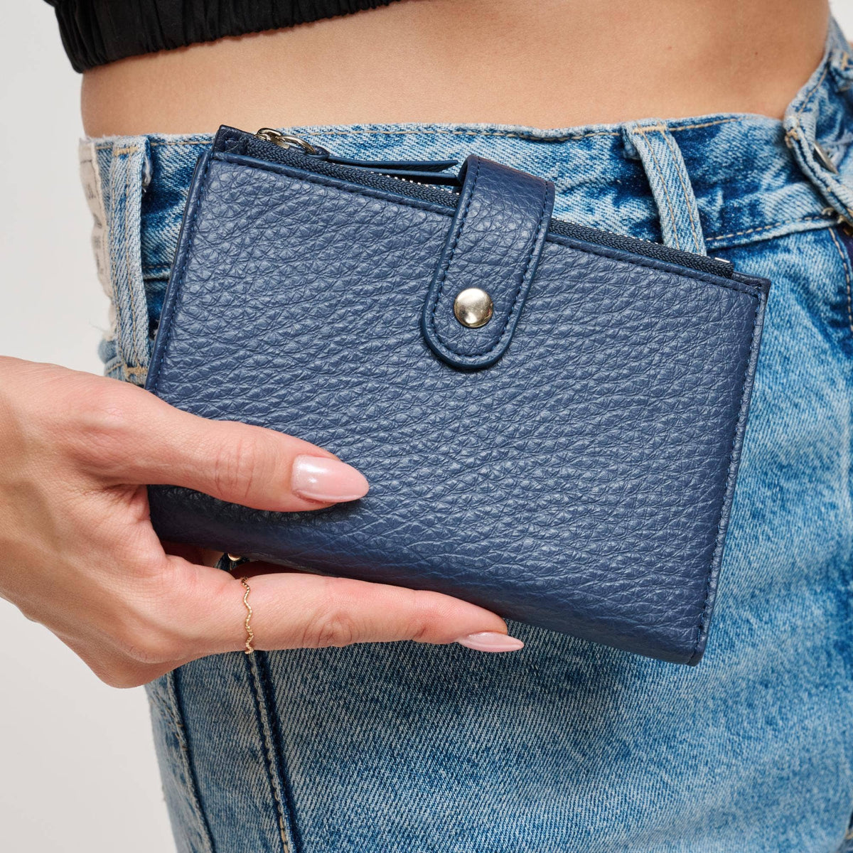 Person holding a blue wallet with jeans in the background