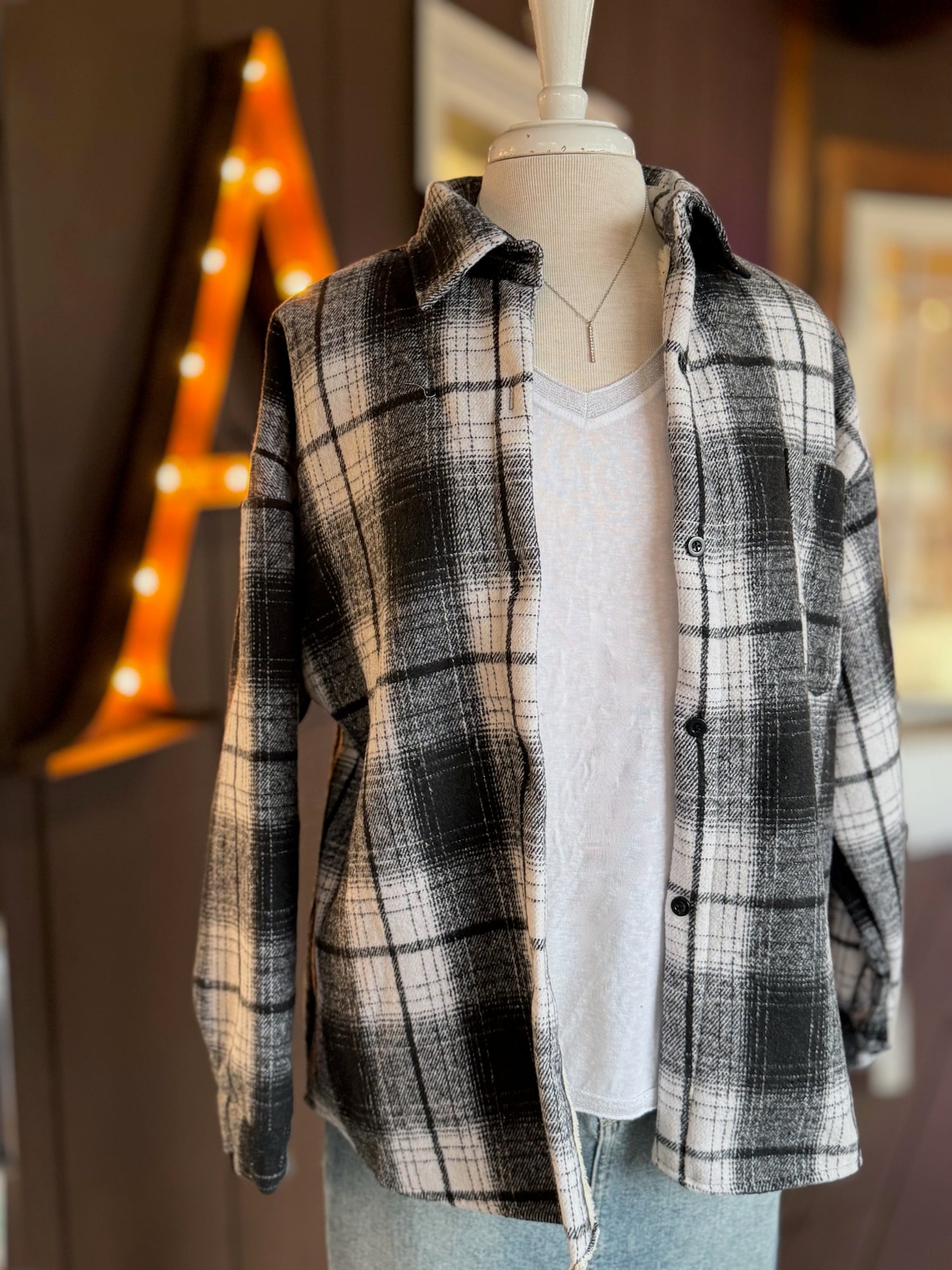 Black and white plaid shacket with sherpa lining, button front, and chest pocket displayed on mannequin over white t-shirt