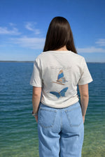Person wearing a t-shirt with butterfly designs by the water