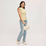 Model carrying the Selena Crossbody in cream by its rolled top handles, featuring soft vegan leather, a gathered silhouette, and polished gold-tone hardware.
