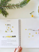 Camping Watercolor Workbook open to fireflies page with painting example, color palette, and outline sketch by Emily Lex